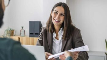 Candidate giving resume to recruiter at desk in workplace